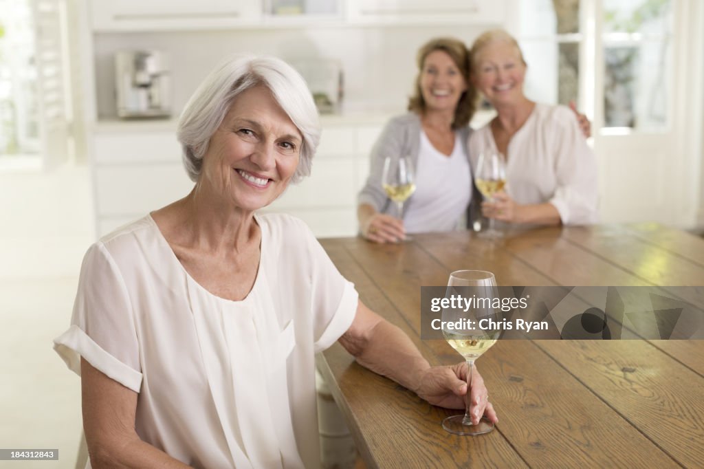 Senior women drinking white wine in kitchen