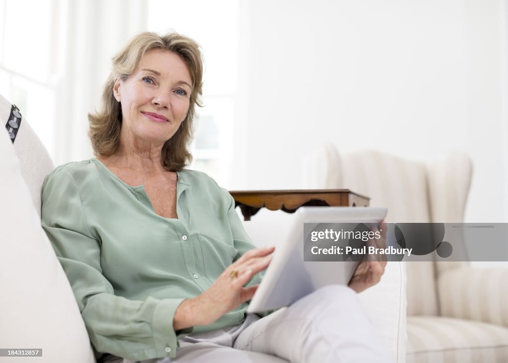 Portrait of senior woman using digital tablet on sofa