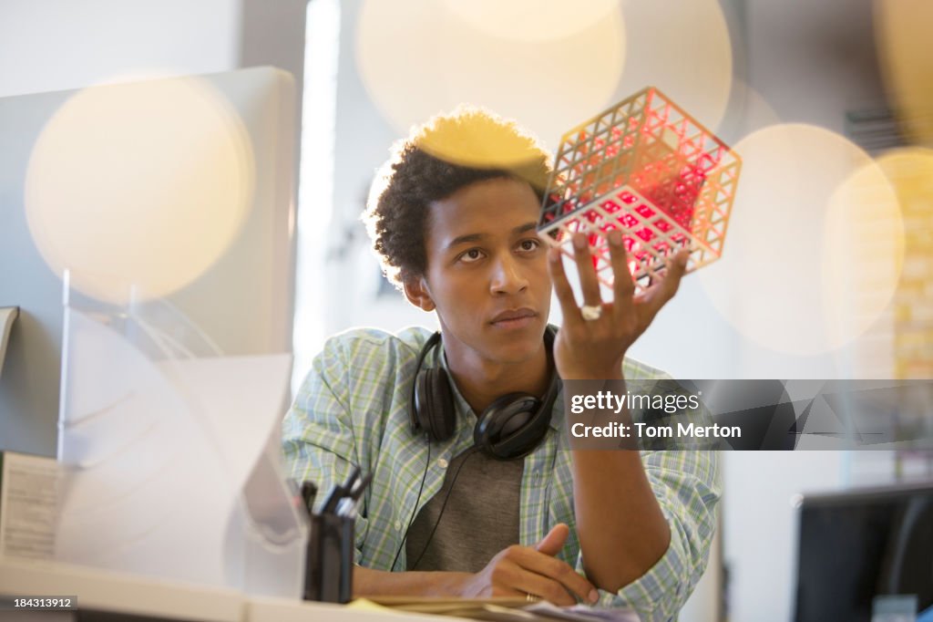 Businessman examining cube at desk in office