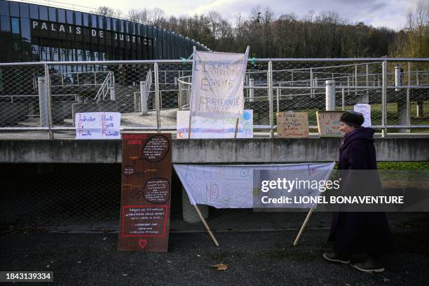 Member of the "Enfance Libre" association walks past banners during a rally, before a hearing of fellow members in front of the criminal court in...