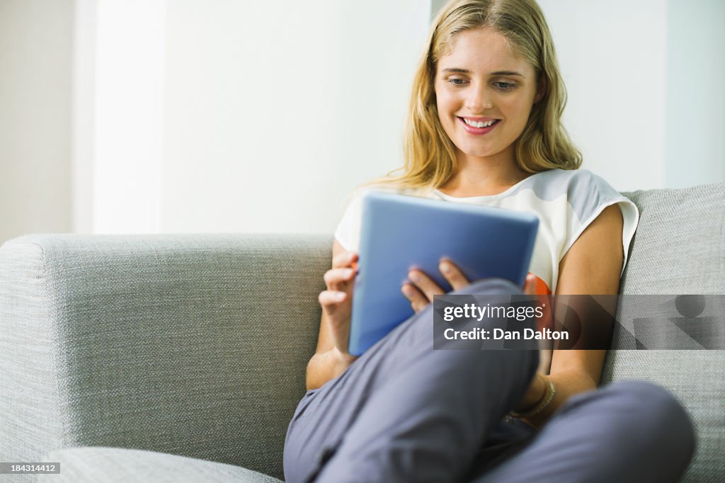 Woman using digital tablet on sofa