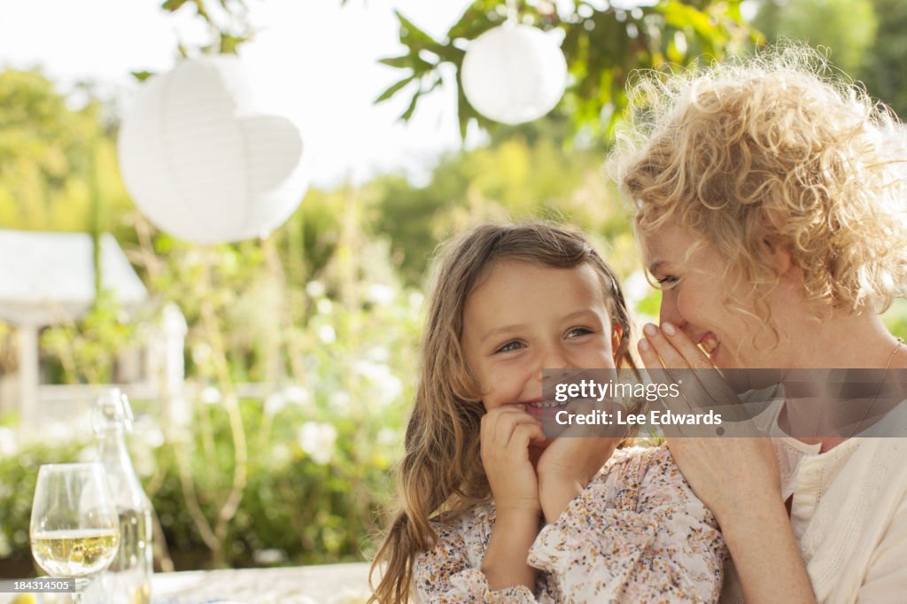 Mother and daughter whispering outdoors