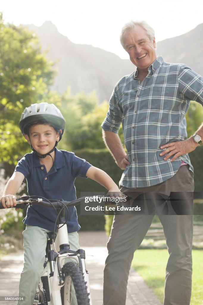 Older man teaching grandson to ride bicycle