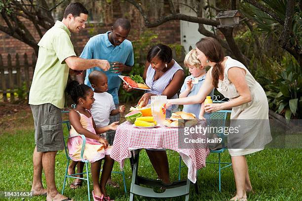 two families at backyard cookout - family eating potato chips stock pictures, royalty-free photos & images