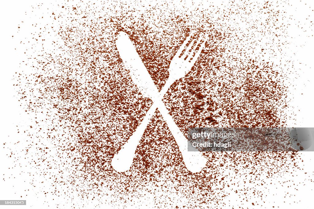 Image in cocoa powder of a knife and spoon outline, on white