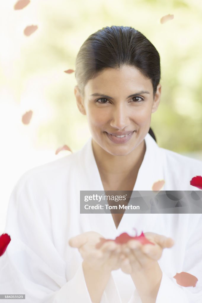 Portrait of smiling woman holding rose petals