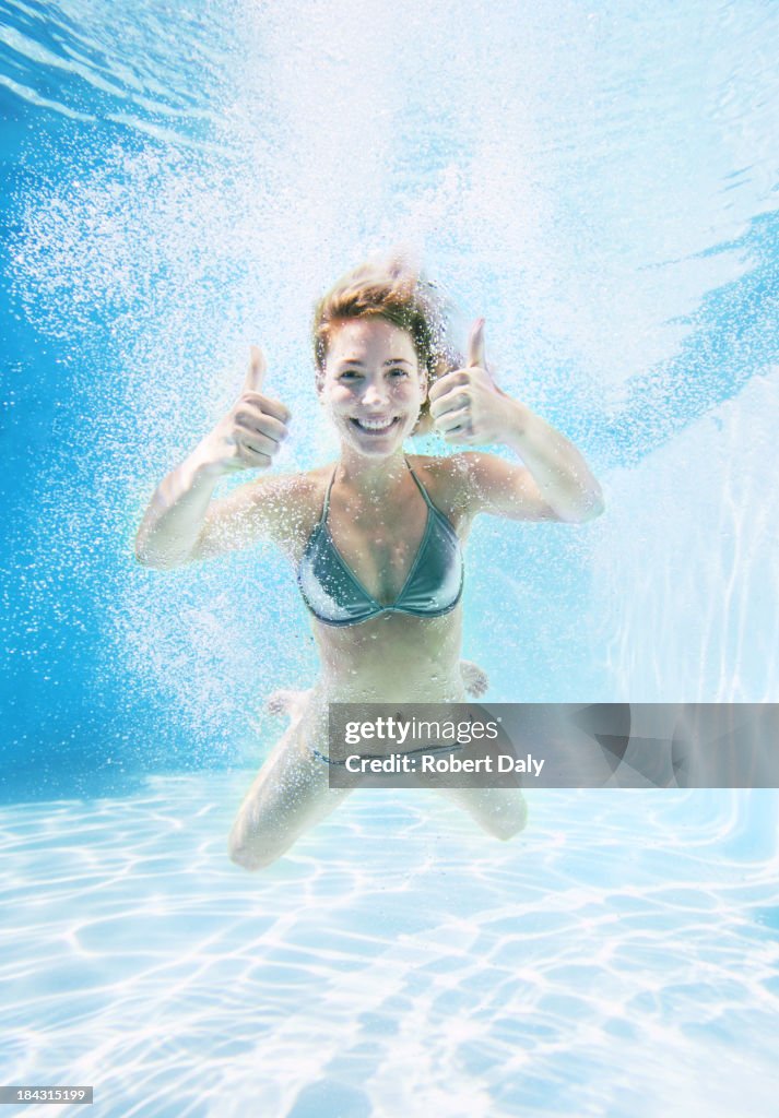 Donna dando Pollice in su sott'acqua in piscina