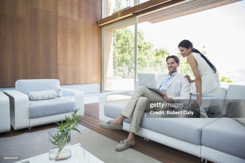 Couple using laptop on sofa