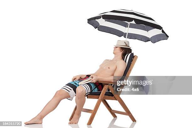 mann entspannen in einem liegestuhl - beach umbrella isolated stock-fotos und bilder