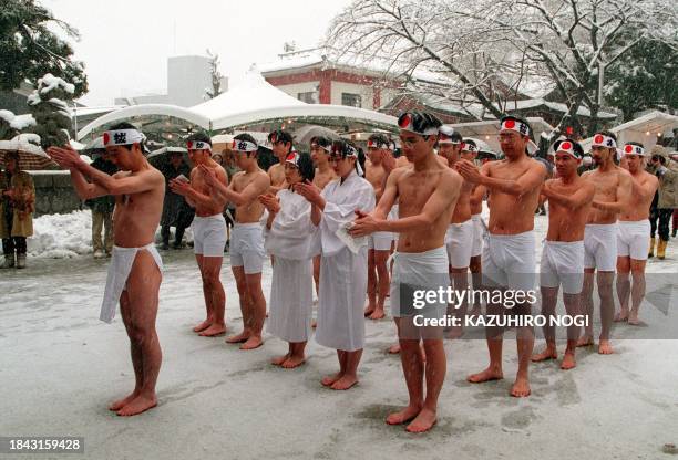 Young people clap their hands in prayer at the Kanda shrine in Tokyo 15 January as they celebrate the nation's Coming of Age Day under heavy snow....