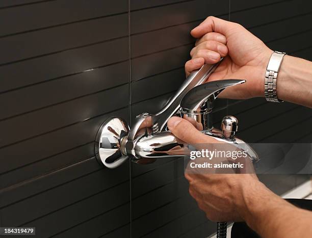 plumber working with a wrench on a silver faucet - household fixture stock pictures, royalty-free photos & images