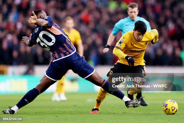 Hee chan Hwang of Wolverhampton Wanderers is challenged by Willy Boly of Nottingham Forest during the Premier League match between Wolverhampton...