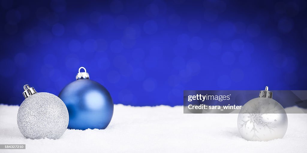 Argento e Blu ciondoli di natale sulla neve, sfondo blu