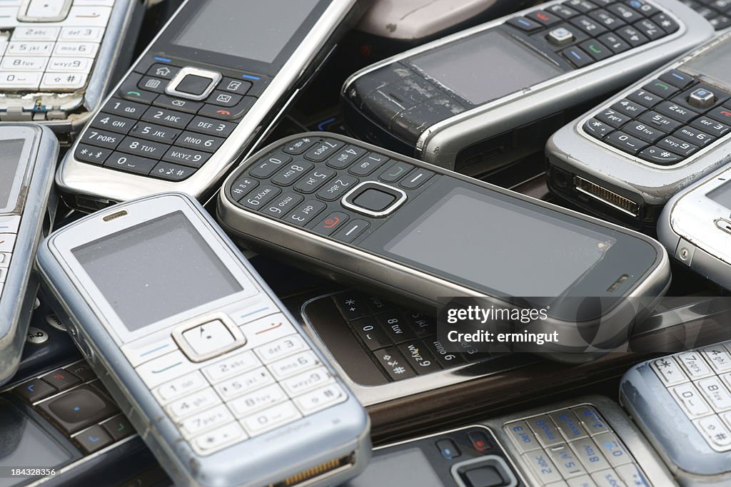 Old used cellphones pile as background