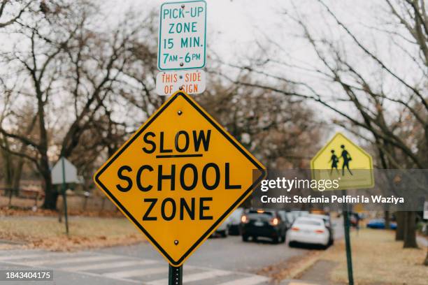 slow school zone sign - zona horaria fotografías e imágenes de stock
