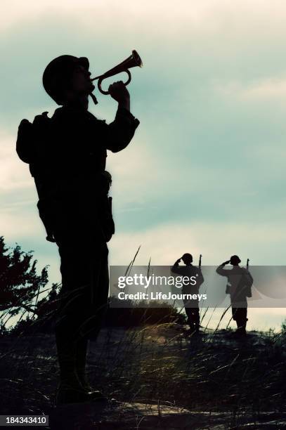 silhouette of wwii  soldier playing taps  at  days  end - bugle stockfoto's en -beelden