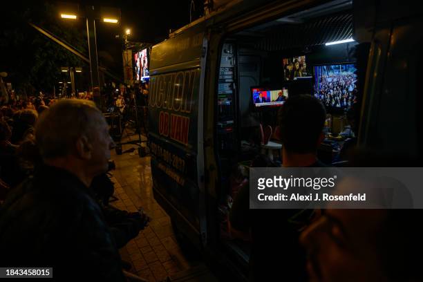 Families of the hostages and their supporters watch a live streaming truck with multiple tv screen including the local news stations during a rally...