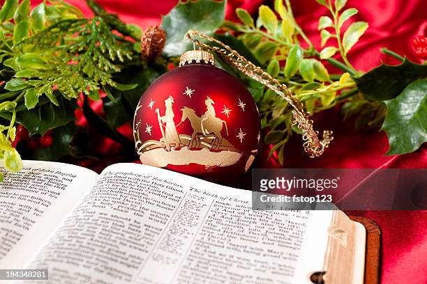 nativity red christmas ornament.  open bible. garland. st. luke. - manger stock pictures, royalty-free photos & images