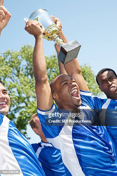 happy soccer team holding up victory trophy - 足球賽事 個照片及圖片檔