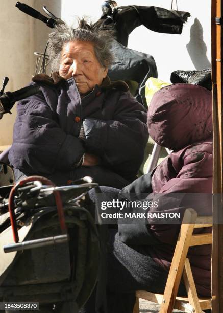 Two elderly Shanghai women sit in the sun to keep warm during the cold winter in Shanghai, 01 February 2007. Although most of the rooms have...