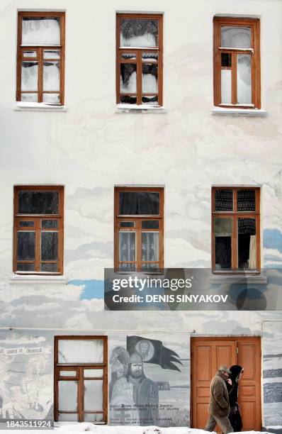 Russian couple walks past a building painted by local artist in the old Russian town of Borovsk, some 90 kms from Moscow, 22 January 2006, as...