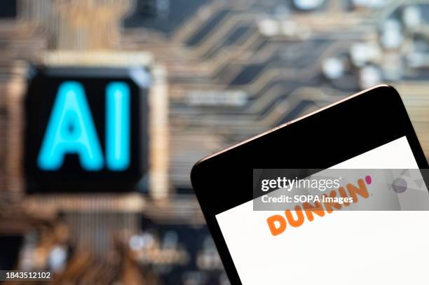 In this photo illustration, the American multinational coffee and snack chain Dunkin' Donuts logo seen displayed on a smartphone with an Artificial...