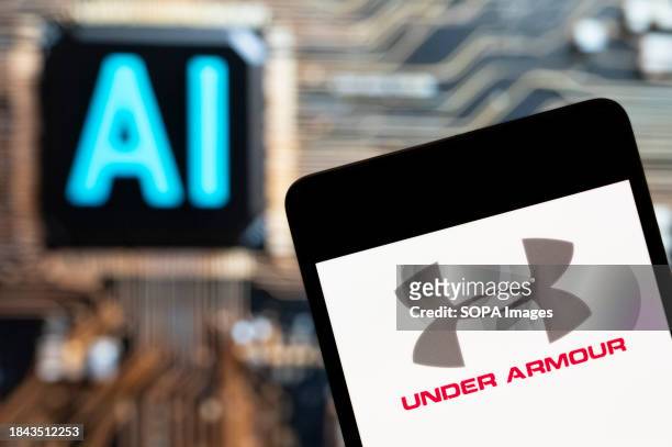 In this photo illustration, the American multinational clothing brand Under Armour logo seen displayed on a smartphone with an Artificial...