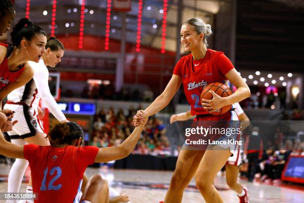 Elisabeth Aegisdottir helps up Asia Boone of the Liberty Lady Flames during their game against the NC State Wolfpack at Reynolds Coliseum on December...