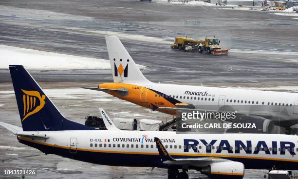 Snow plough drives past Monarch and Ryanair planes at Gatwick airport, West Sussex, on December 19, 2010. Ryanair was forced to cancel 84 of its...