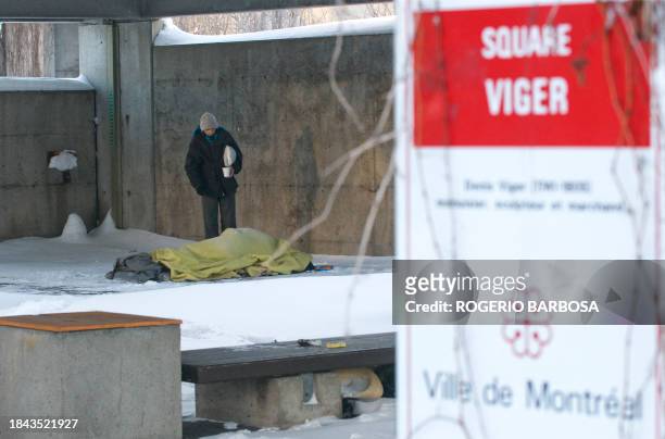 Man checks on a homeless person sleeping on a snow covered sidewalk on December 23, 2008 in Montreal, Quebec, Canada. A week after a homeless man was...