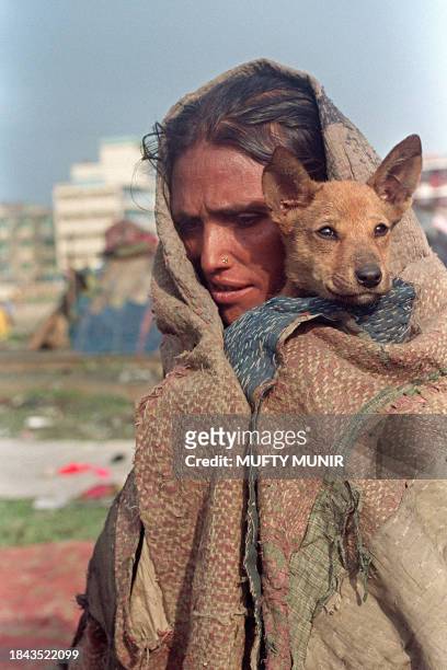 Woman at a slum near Dhaka's railway terminal shares a guilt with her pet dog 29 December 1991 as continual cold spell intensified after heavy rains...