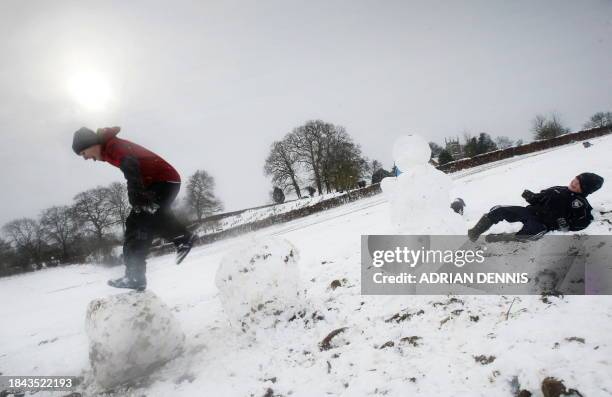 Boy jumps from one giant snowball to another while playing in a field close to Hartley Wintney in Hampshire on February 3, 2009. Parts of the UK are...