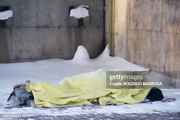 Homeless person sleeps on a snow covered sidewalk on December 23, 2008 in Montreal, Quebec, Canada. A week after a homeless man was found dead in...