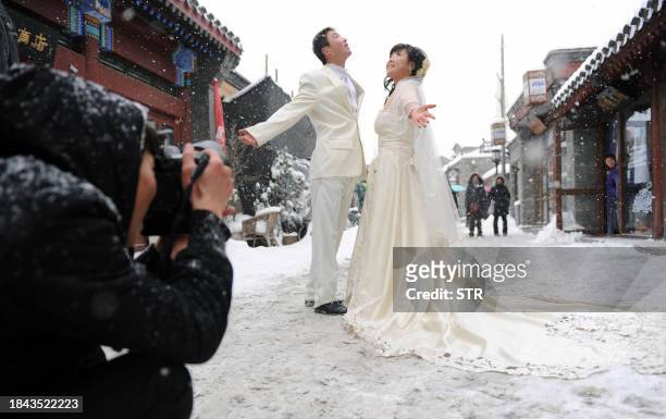 Chinese wedding couple poses for photos after a heavy snowfall in Beijing on January 3, 2010. The Chinese capital received its heaviest daily...
