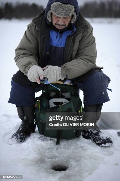 Man fishes through the ice after digging a hole in a frozen river on December 17, 2008 in Rovaniemi. In this region the ice is about 20 centimeters...