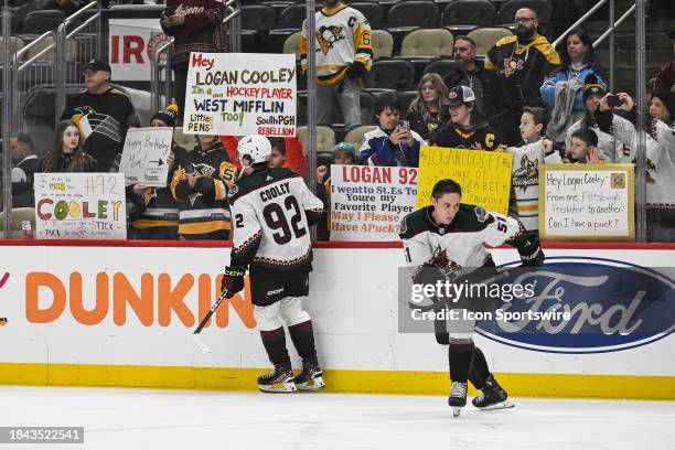 Fans hold signs for Pittsburgh native Arizona Coyotes Center Logan Cooley as he warms up before the game between the Pittsburgh Penguins and the...