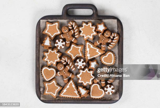 holiday gingerbread cookies decorated with icing sugar. in the shape of a christmas tree, a star, snowflakes, a gingerbread man with a cane, a heart. on a wooden plate. white background. top view. christmas. new year - rustic star stock pictures, royalty-free photos & images