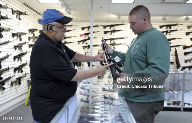 Roger Krahl, president of R Guns, left, gives information to Zack Johnson about an R Guns-brand TRR15 model rifle at Krahl's gun store on Saturday,...