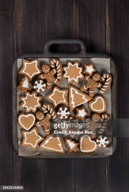 holiday gingerbread cookies decorated with icing sugar. in the shape of a christmas tree, a star, snowflakes, a gingerbread man with a cane, a heart. on a wooden plate. dark wooden background. top view. christmas. new year - rustic star stock pictures, royalty-free photos & images