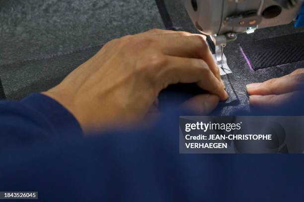 This photograph taken on November 23, 2023 shows Davy Dao, founder of textile brand Dao, sews a bag made with linen vegetable leather at company...