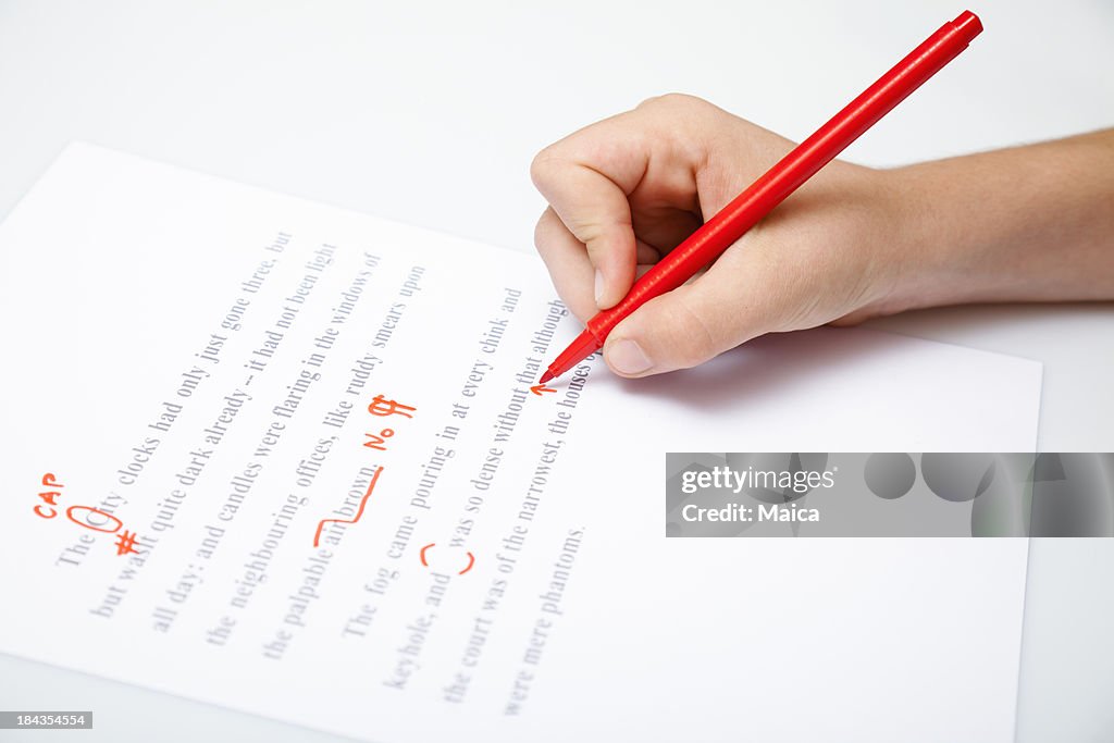 Person holding a pencil proofreading a document