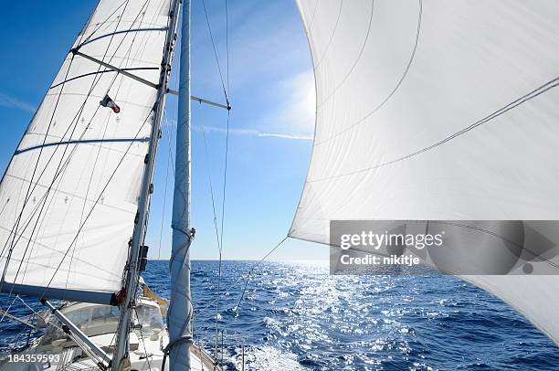 sailing boat with the sun shingn behing sail - jib stock pictures, royalty-free photos & images