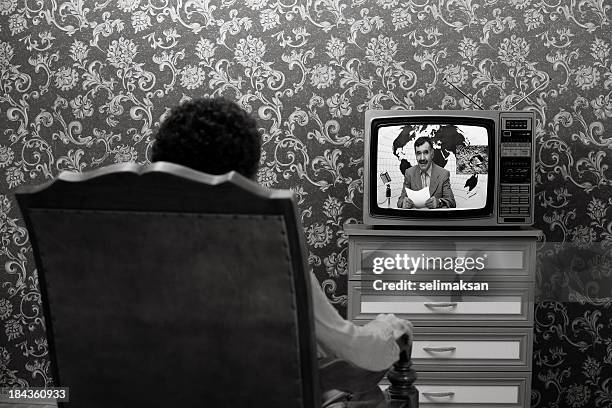 back view of man sitting and watching news on television - retro television stock pictures, royalty-free photos & images