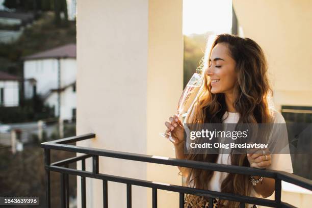 woman relaxing on terrace with glass of cold champagne. celebration concept, pleasure and positive emotions. - cipresso stock-fotos und bilder