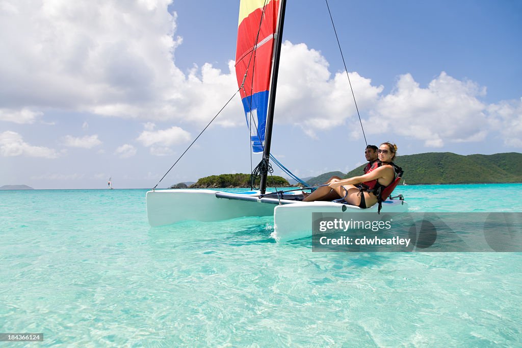 Casal velejar um catamarã no Caribe