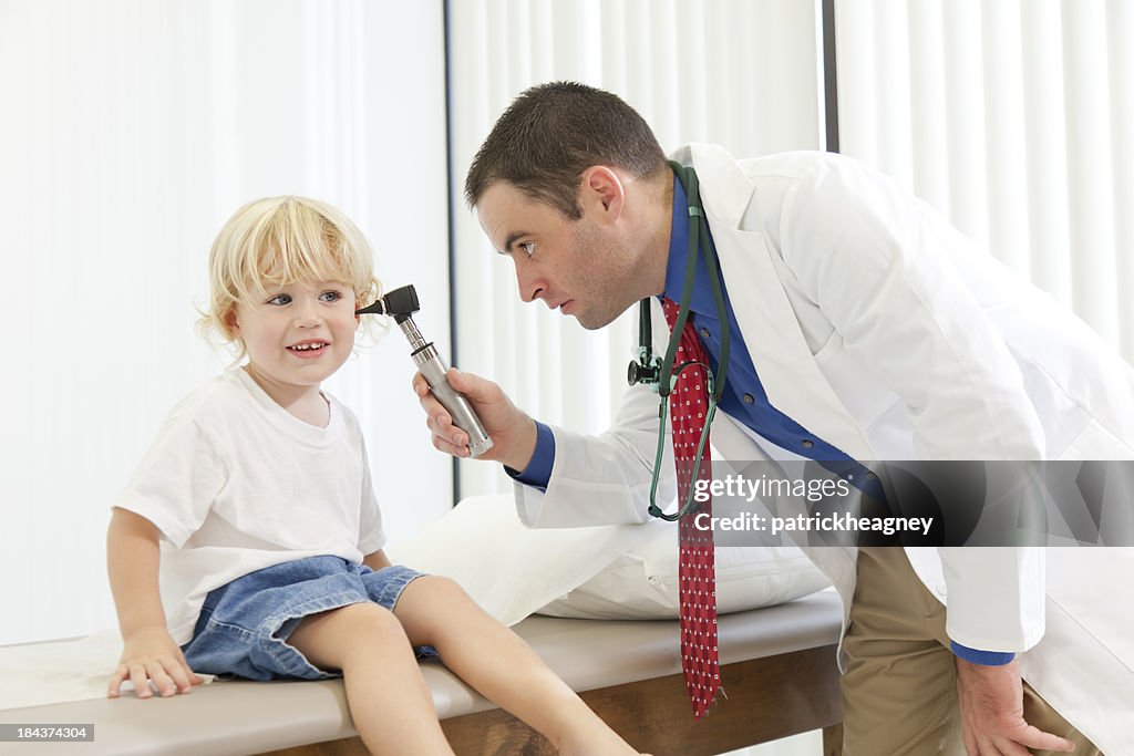 Kinderarzt blickt in Kind die Ohren