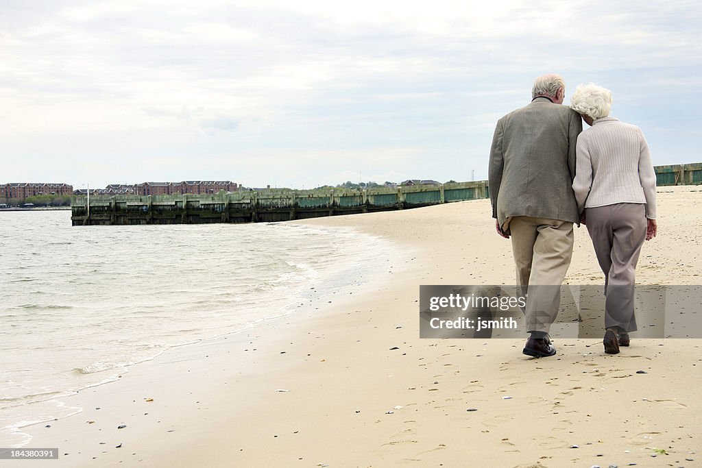 Senior Couple Holding Hands And Walking On Beach