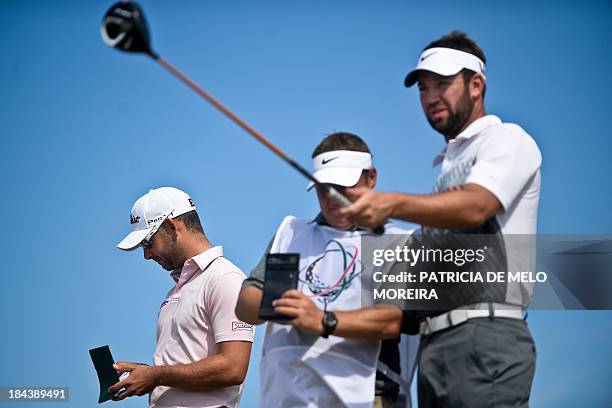 Scottish golfer Scott Jamieson speaks to his caddie as British golfer Paul Waring takes notes at the 1st hole during the last day of the Portugal...