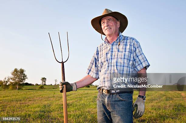 senior farmer smiling in a field - pitchfork agricultural equipment bildbanksfoton och bilder