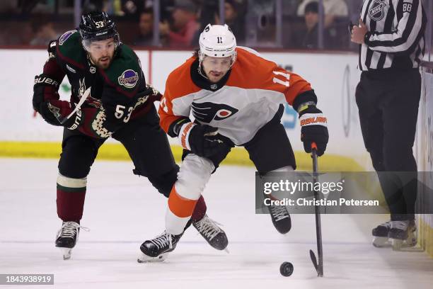 Travis Konecny of the Philadelphia Flyers skates with the puck ahead of Michael Carcone of the Arizona Coyotes during the third period of the NHL...